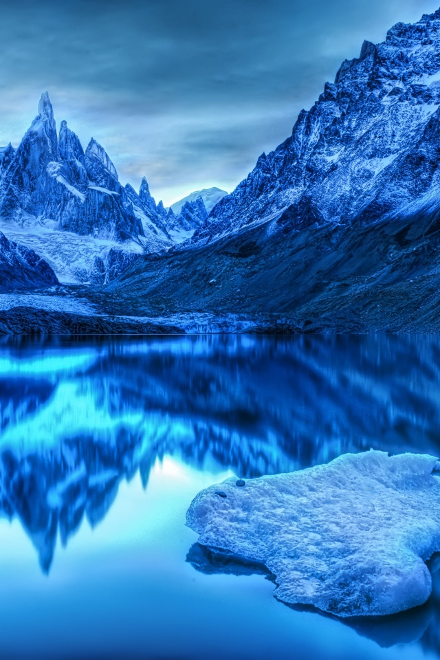 Заснеженные горы отражаются в воде в сумерках