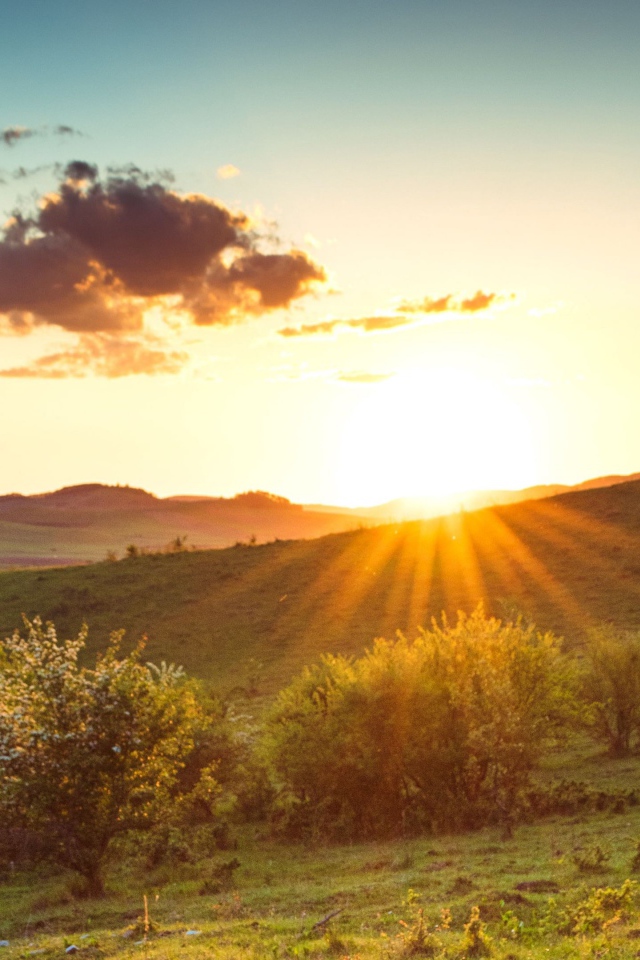 Яркое летнее солнце встает из-за гор 