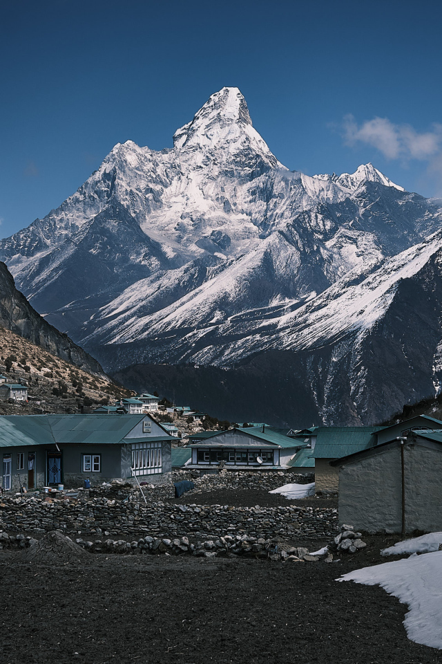 Поселок на фоне заснеженных гор под голубым небом 