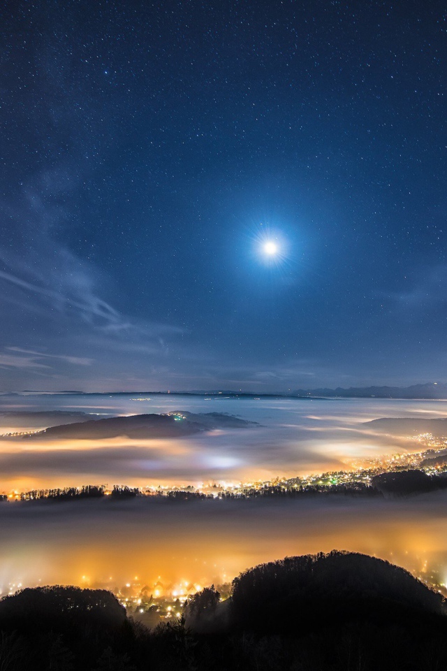 Вид с горы на покрытый туманом ночной город 