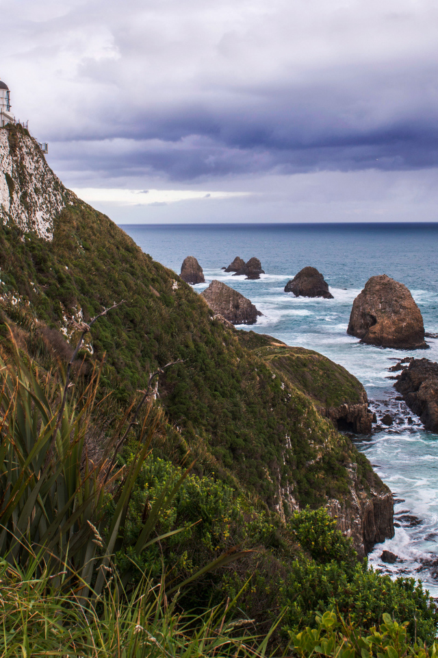 Маяк на вершине утеса у моря под грозовым небом