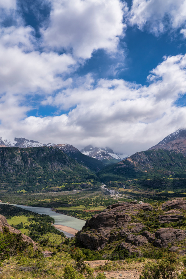 Белые облака в голубом небе над покрытыми зеленью горами