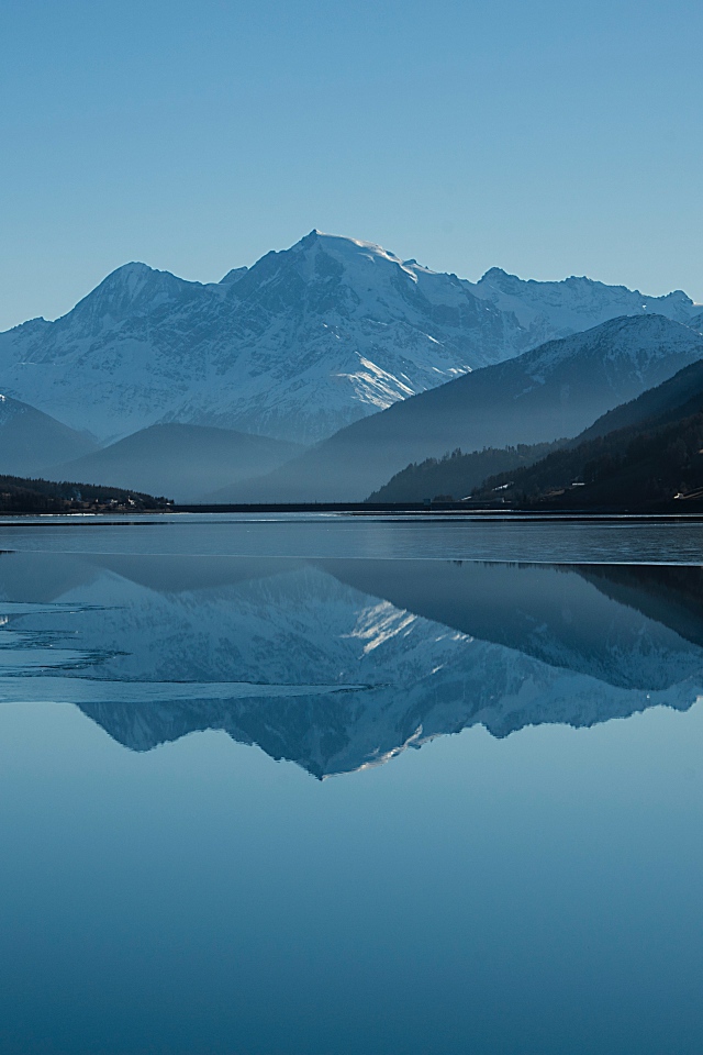 Холодное озеро покрывается льдом у гор