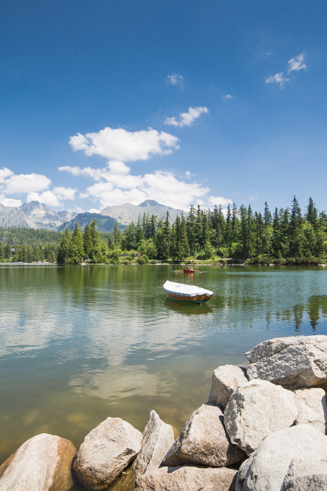 Лодка в озере на фоне гор под голубым небом