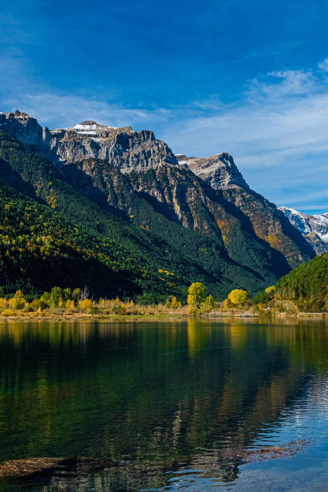 Холодная вода в чистом озере у горы под голубым небом