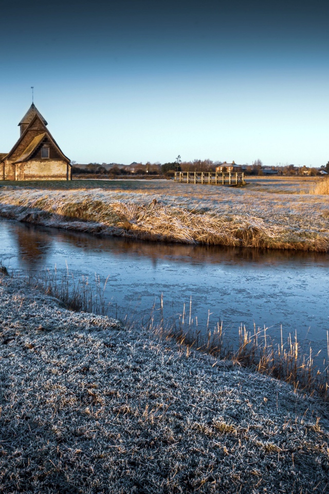 Иней покрывает землю холодным утром у реки