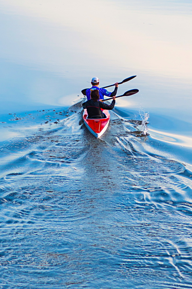 Два спортсмена на лодке плывут по реке 