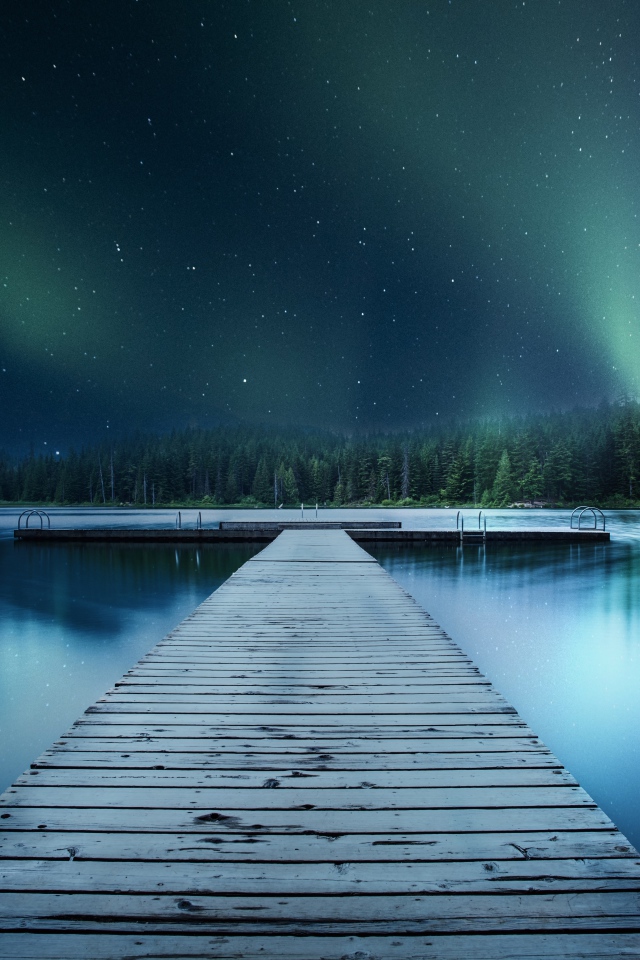 Wooden bridge on the lake under a beautiful night sky