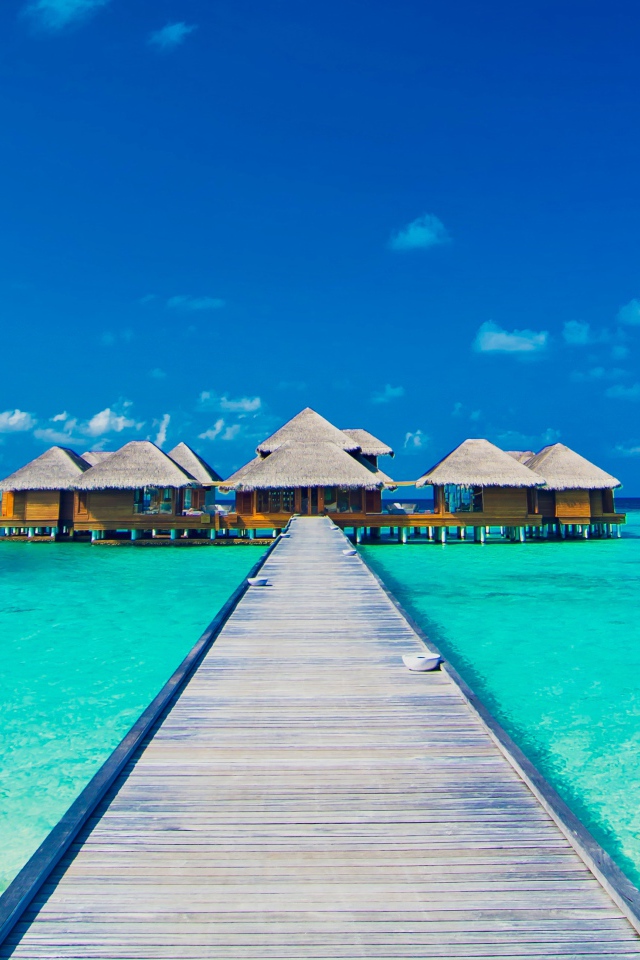Деревянный мост к домам на сваях в голубом океане 