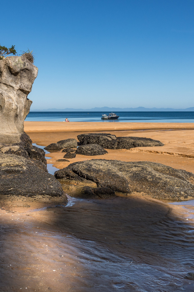 Большие камни на берегу на мокром песке у моря летом 