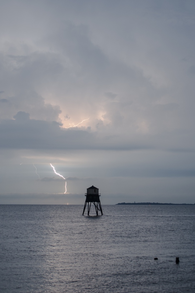Старая башня в море на фоне грозы 