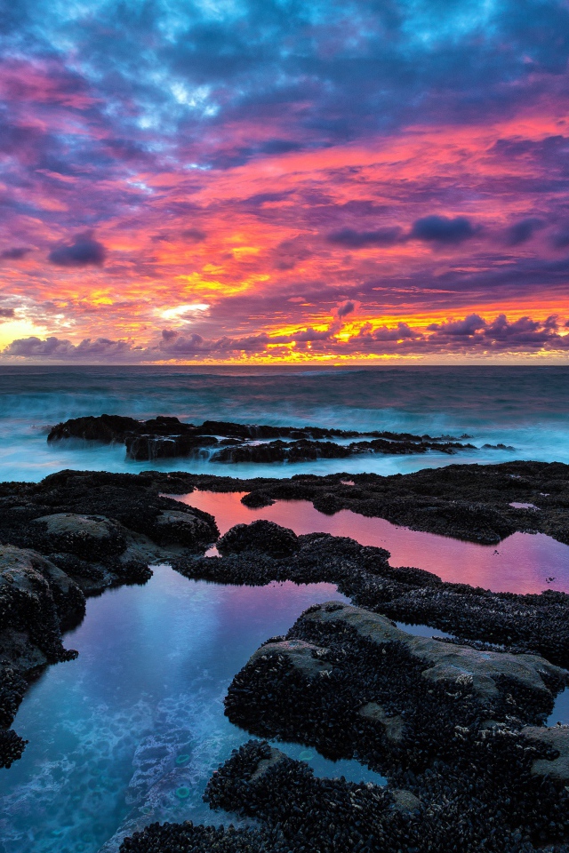 Восход яркого солнца над камнями в море