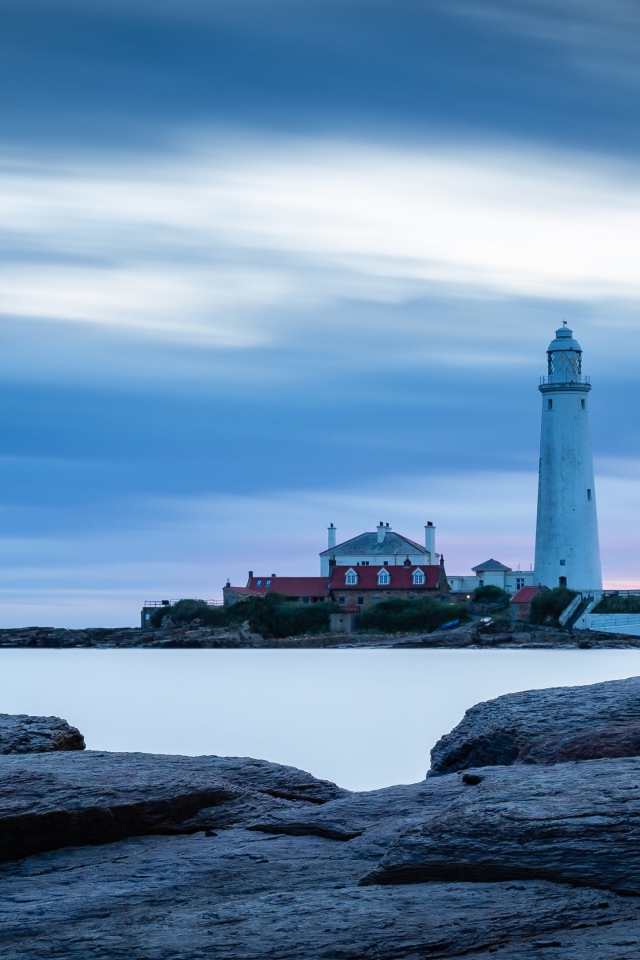 Вид с каменного берега на маяк в море 