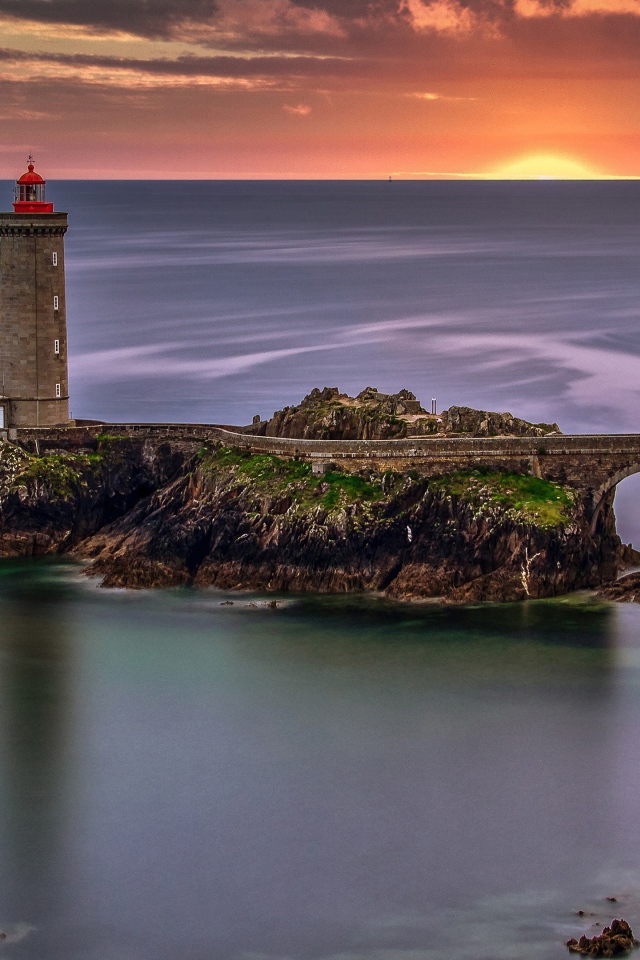 Вид на спокойное море и маяк на закате солнца 