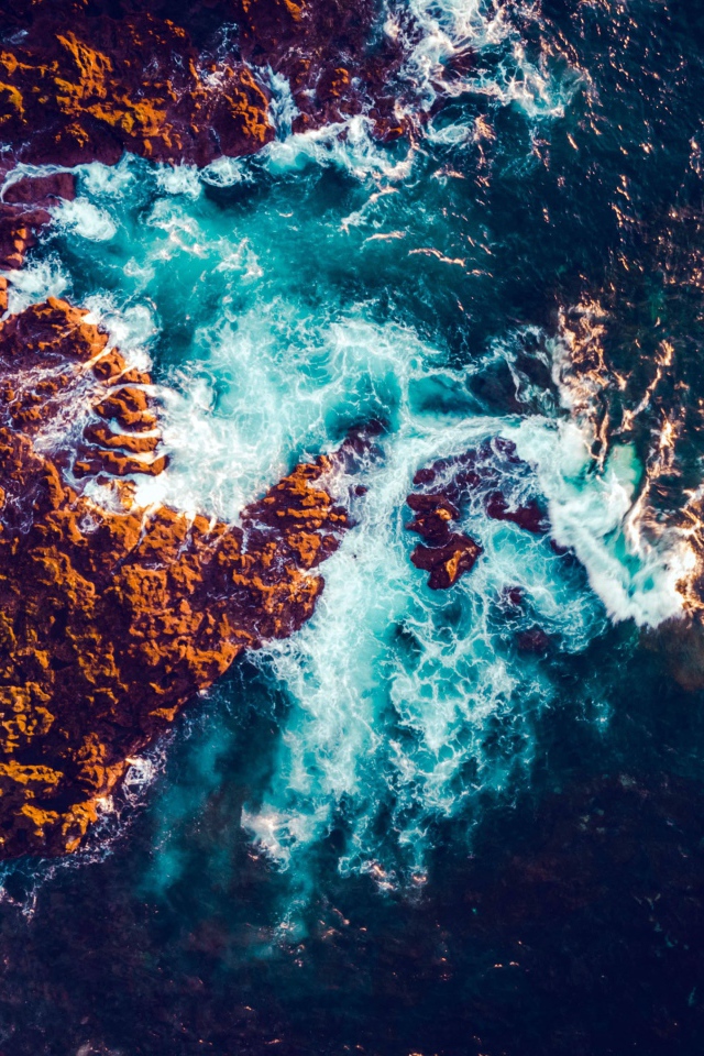 Белые морские волны бьются об камни, вид сверху