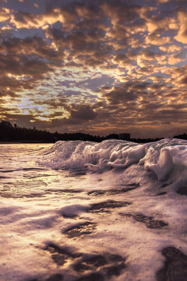 Белые волны на песке на рассвете 