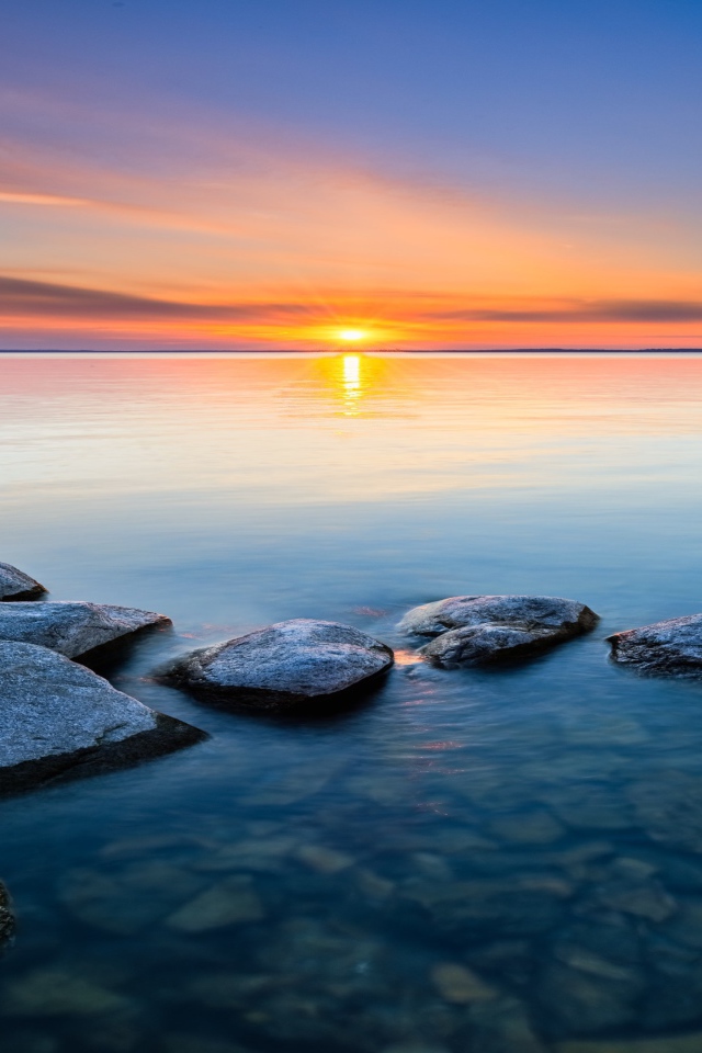 Большие камни в воде на закате яркого летнего солнца 