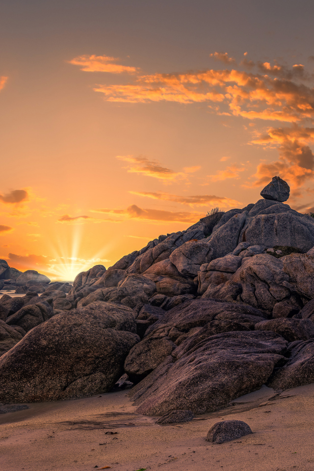 Маяк на берегу каменного берега на закате 