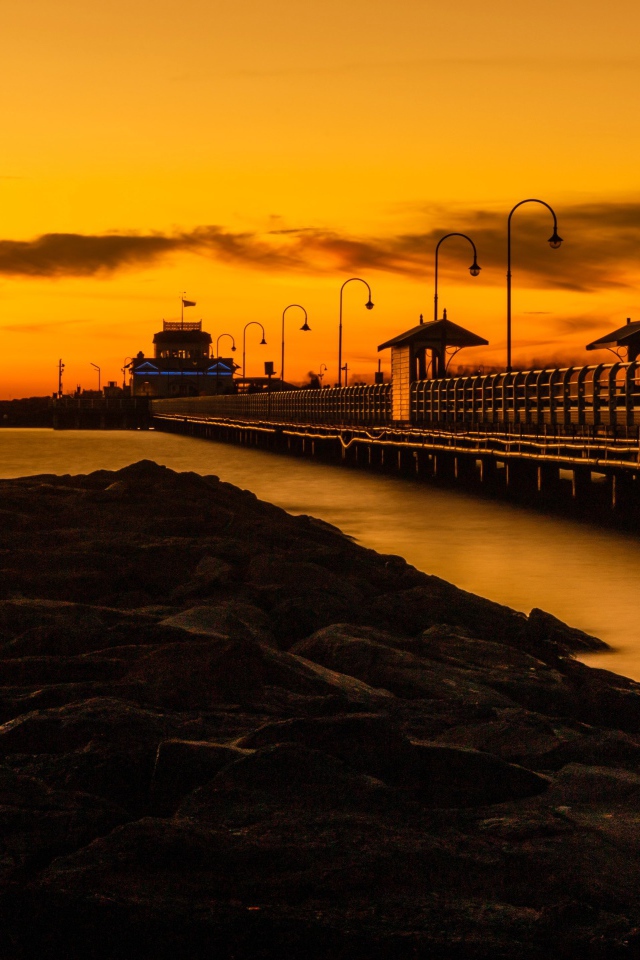 Длинный мост на морском побережье на закате 