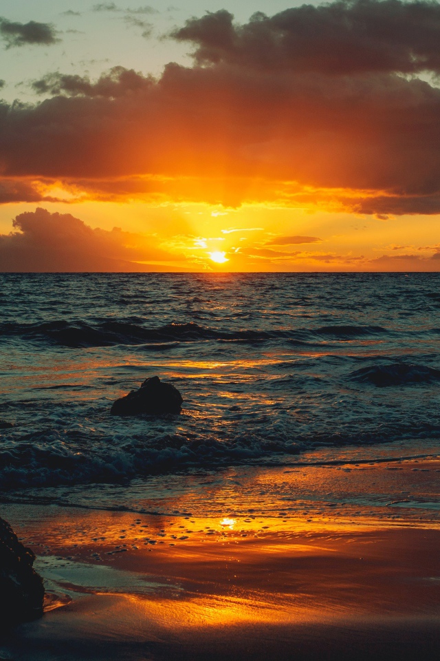 Мокрый песок на берегу океана на закате