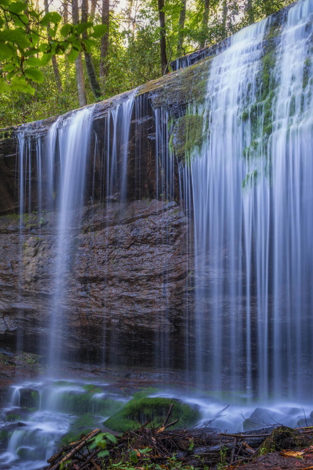 Холодная вода водопада стекает по мокрой скале