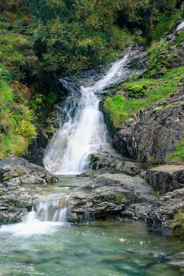 Горный ручей стекает по камням в реку 