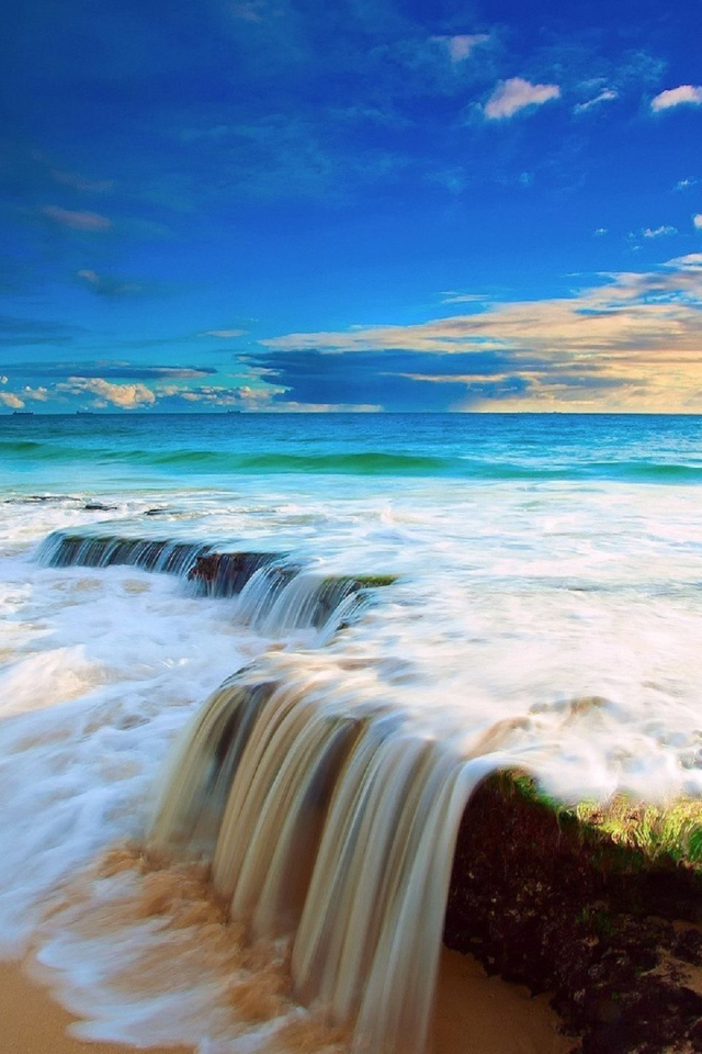 Белые волны бушующего океана на песке под голубым небом