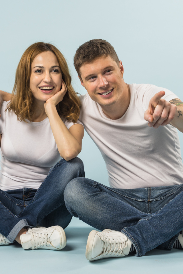 Мужчина и девушка сидят на полу на голубом фоне