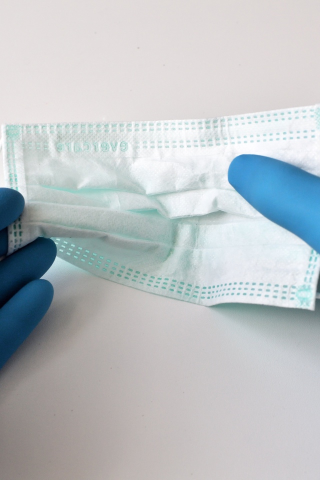 Руки в медицинских перчатках держат маску 