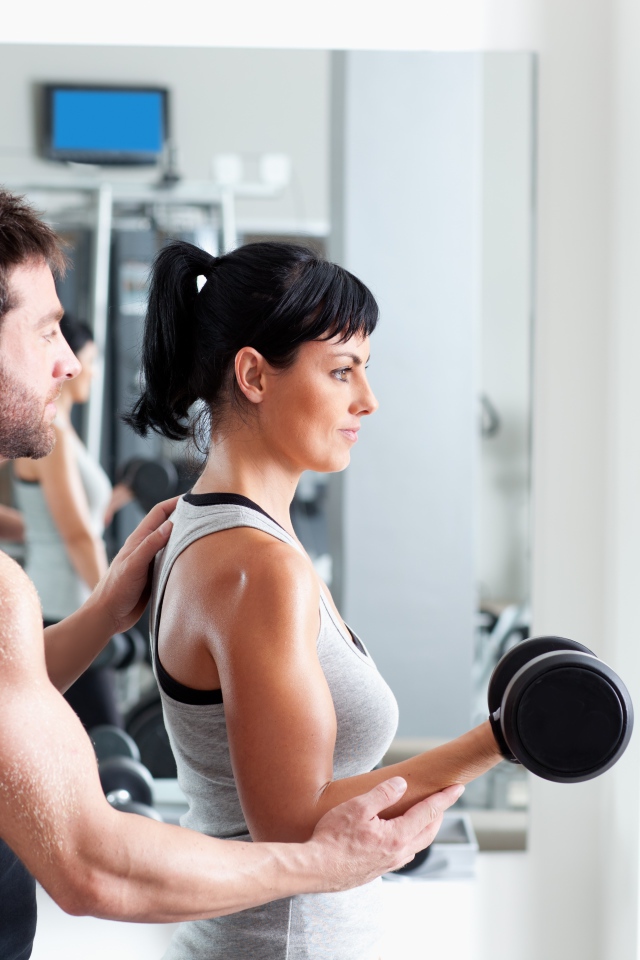 Девушка занимается в спортзале с тренером