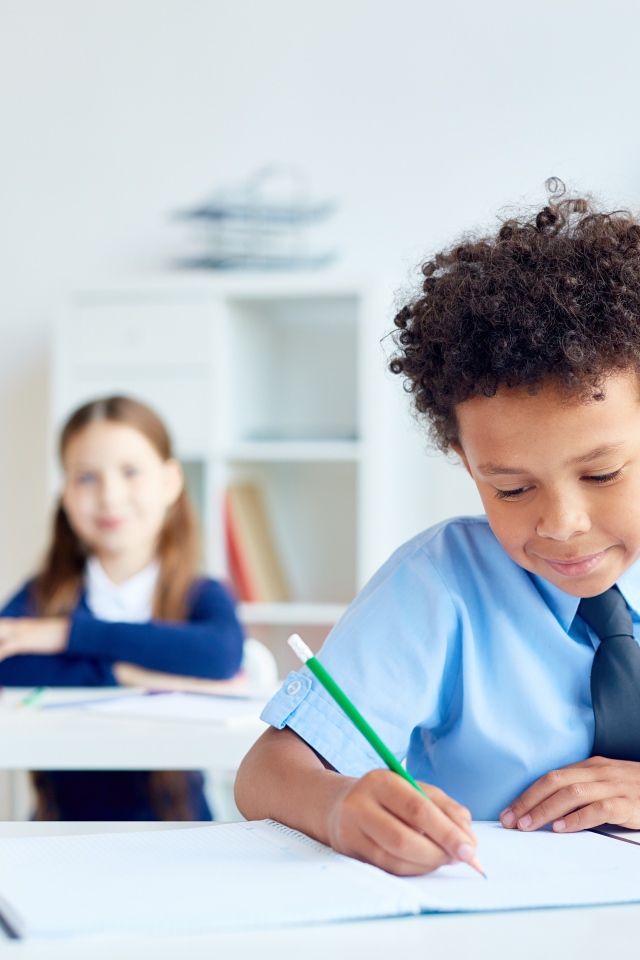 Маленький мальчик сидит за партой в классе