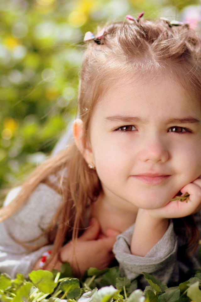 Красивая маленькая кареглазая девочка лежит на траве 