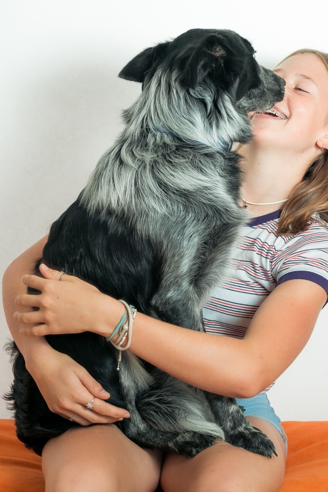 Веселая девочка с собакой в руках 