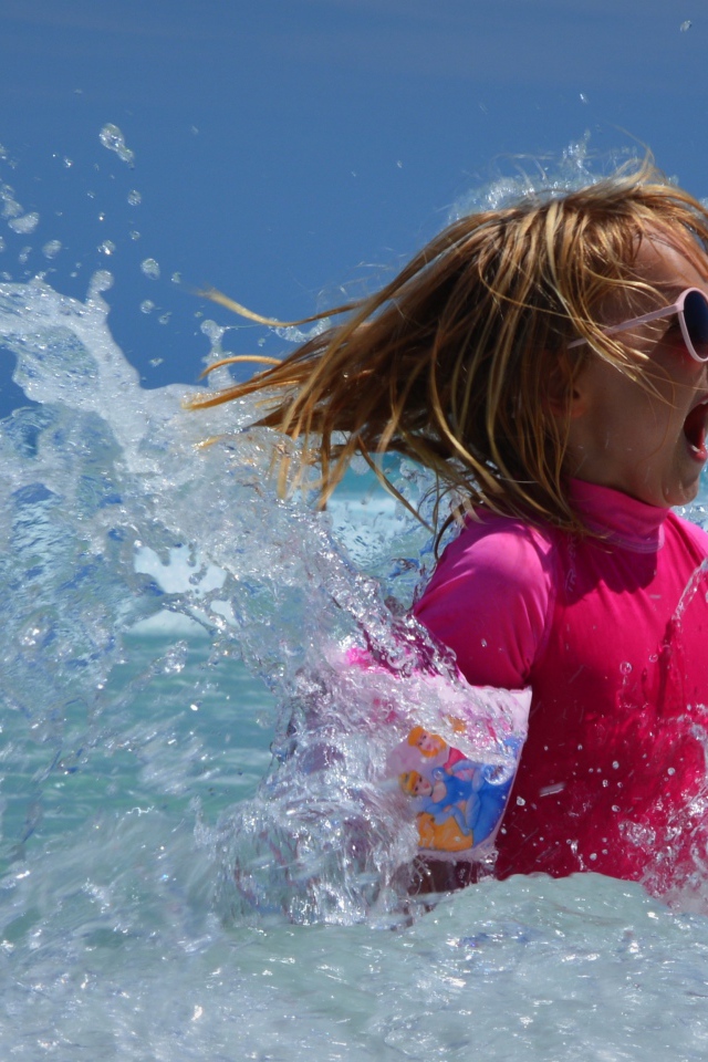 Веселая маленькая девочка купается в море летом