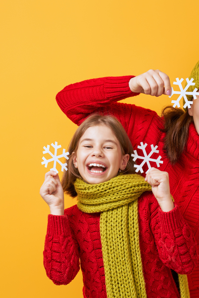 Веселые мама и дочка в красных свитерах на оранжевом фоне