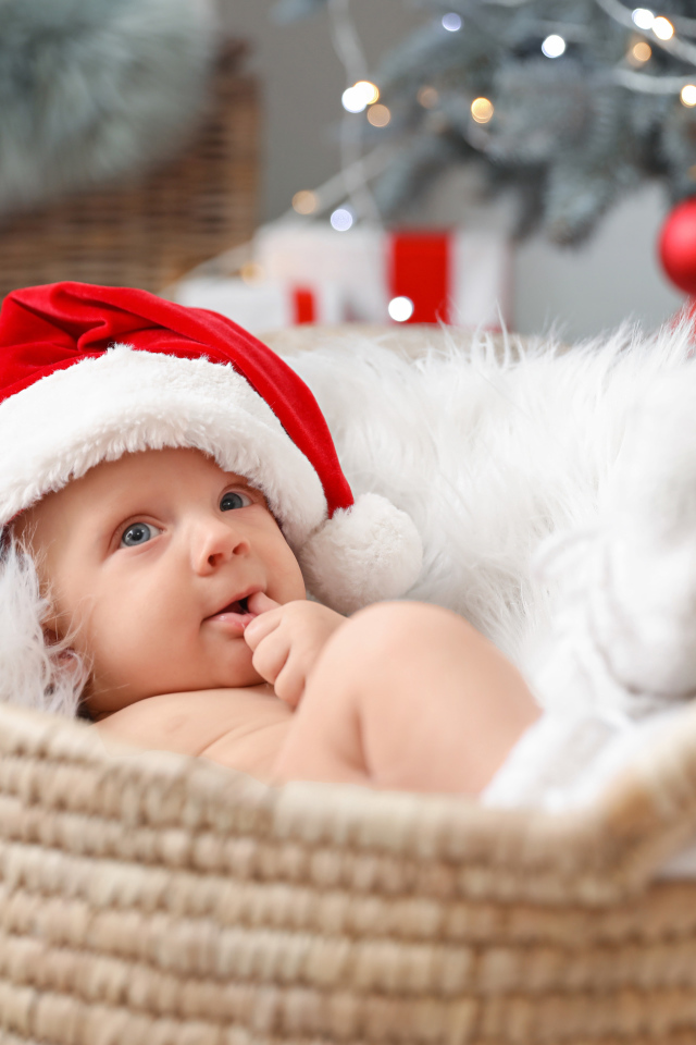 Милый малыш в шапке Санта Клауса лежит в корзине