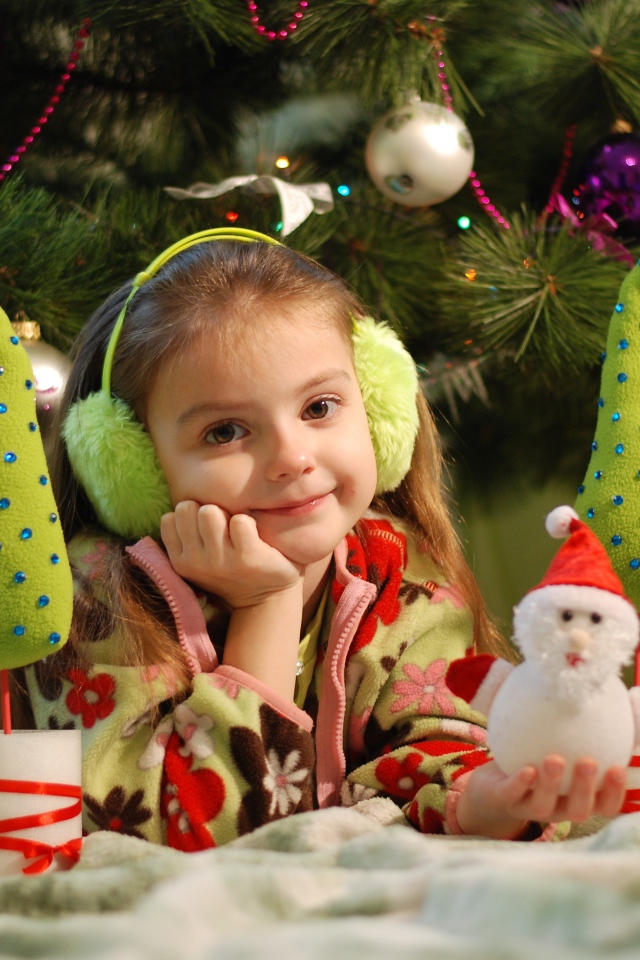 Милая маленькая девочка с игрушками под елкой 