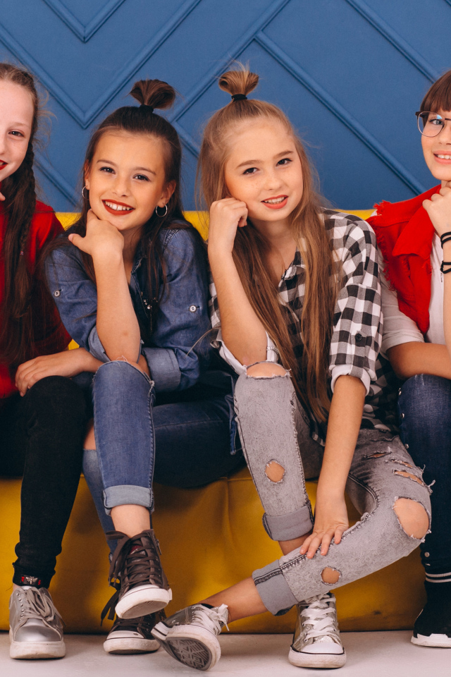 Четыре модных девочки сидят на диване 