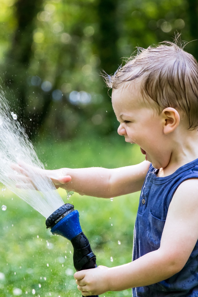 Смешной маленький мальчик играет с водой 