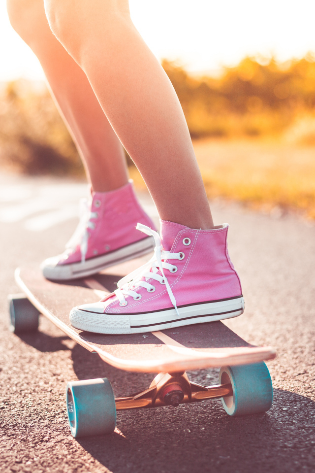 Девочка в розовых кедах едет на скейтборде