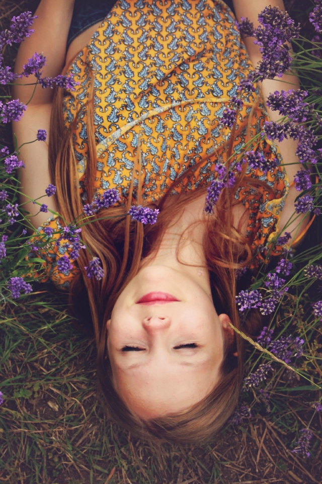 Девочка с закрытыми глазами лежит на земле с фиолетовыми  цветами