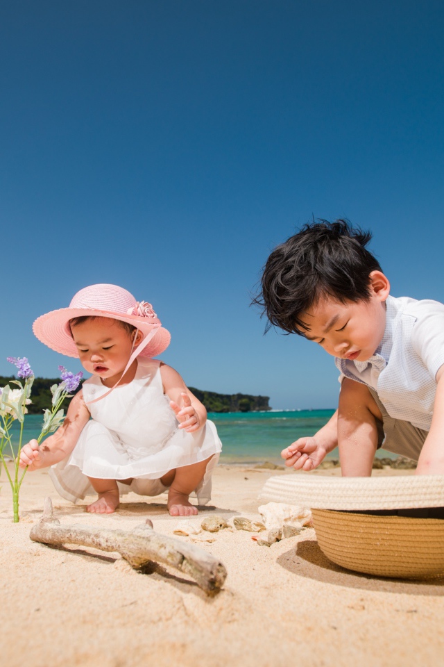 Маленькие дети азиаты играют на песке у моря 