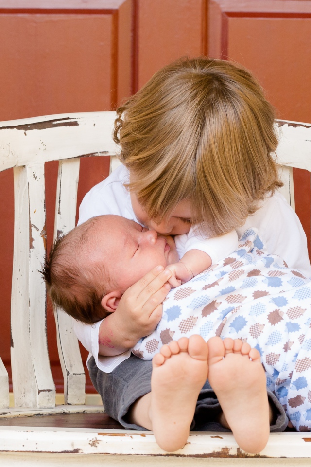 Маленькие мальчик держит брата на руках 
