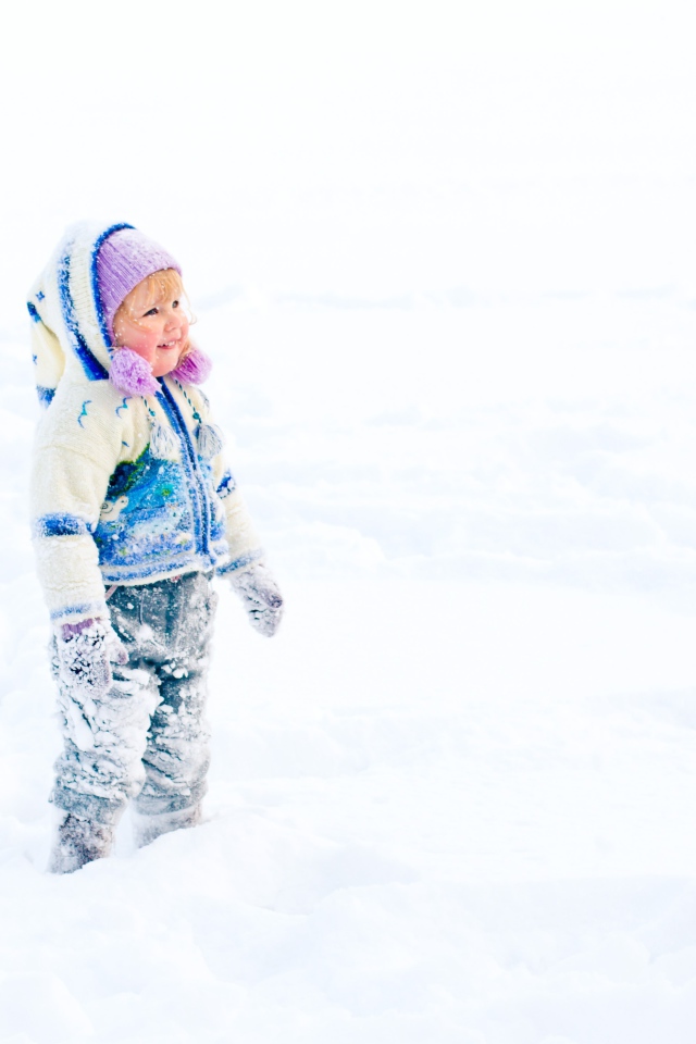Маленькая веселая девочка гуляет по снегу