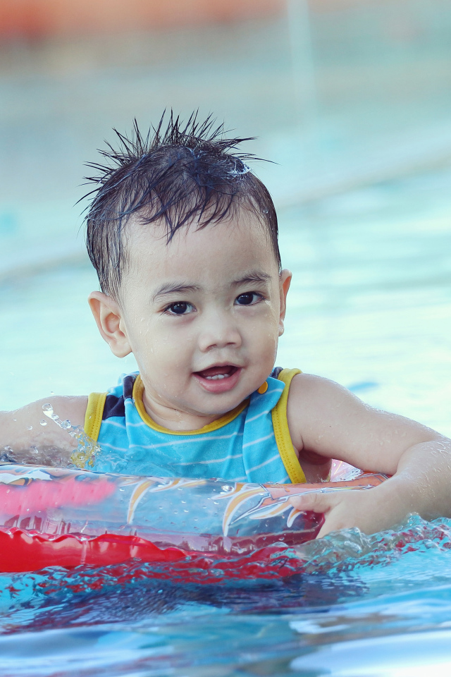 Маленький ребенок со спасательным кругом в бассейне 