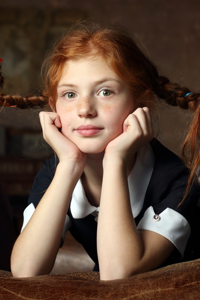 Маленькая смешная девочка с косами в школьной форме 