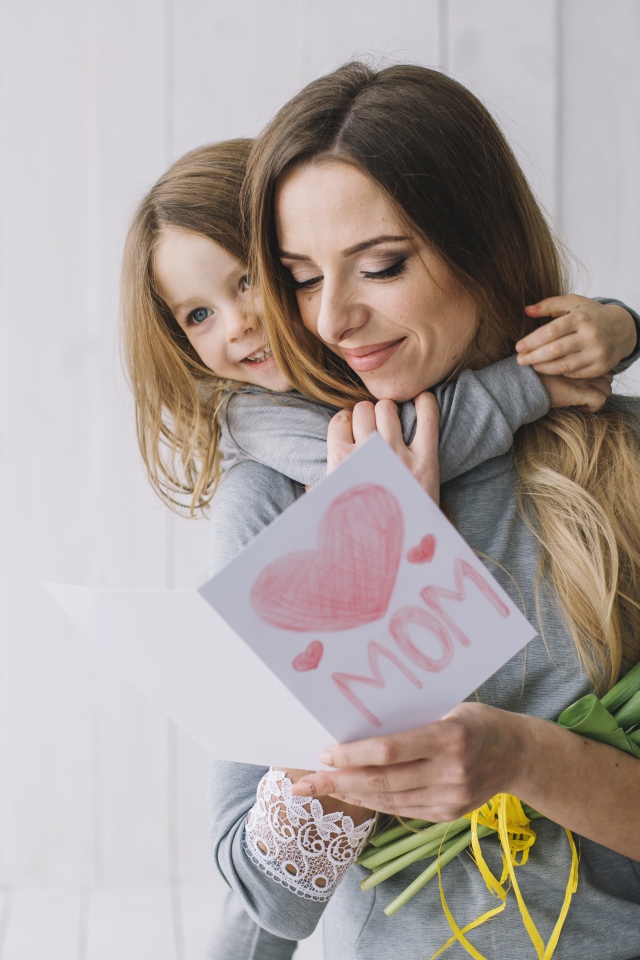 Маленькая девочка подарила маме открытку и букет тюльпанов