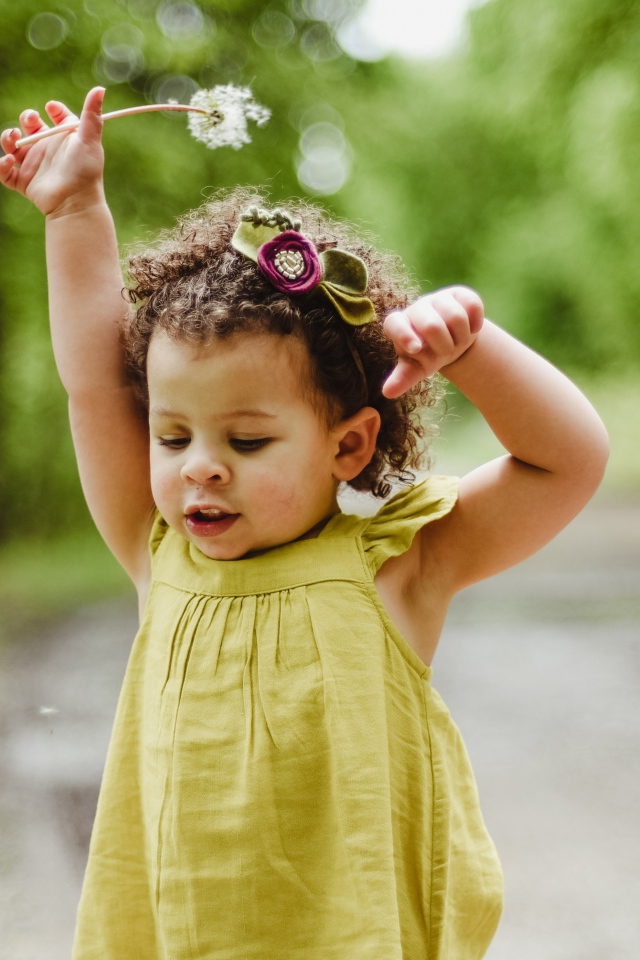 Маленькая девочка в платье с одуванчиком в руке