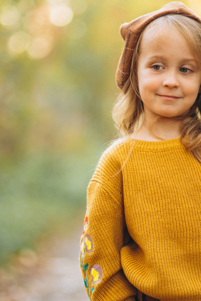 Маленькая девочка в свитере гуляет в лесу