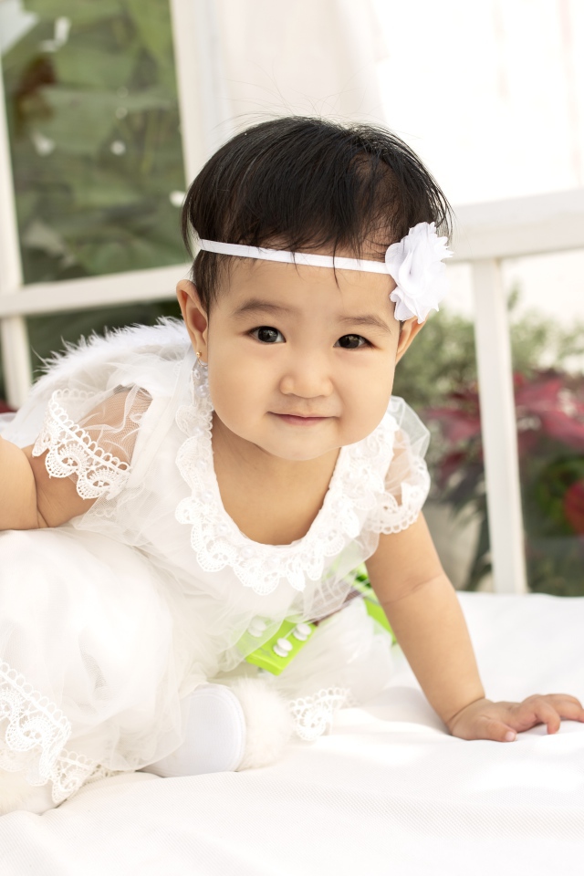 Маленькая девочка в белом платье с леденцом в руке